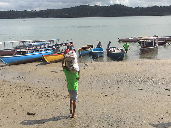 Pescador carregando cesta básica recebida e indo para seu barco