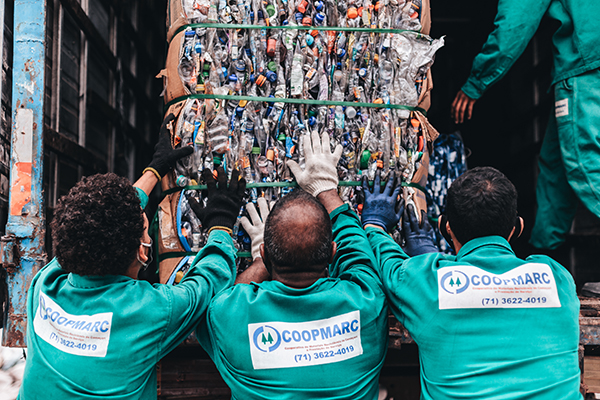 Homens de uma cooperativa descartando resíduos plásticos para reciclágem